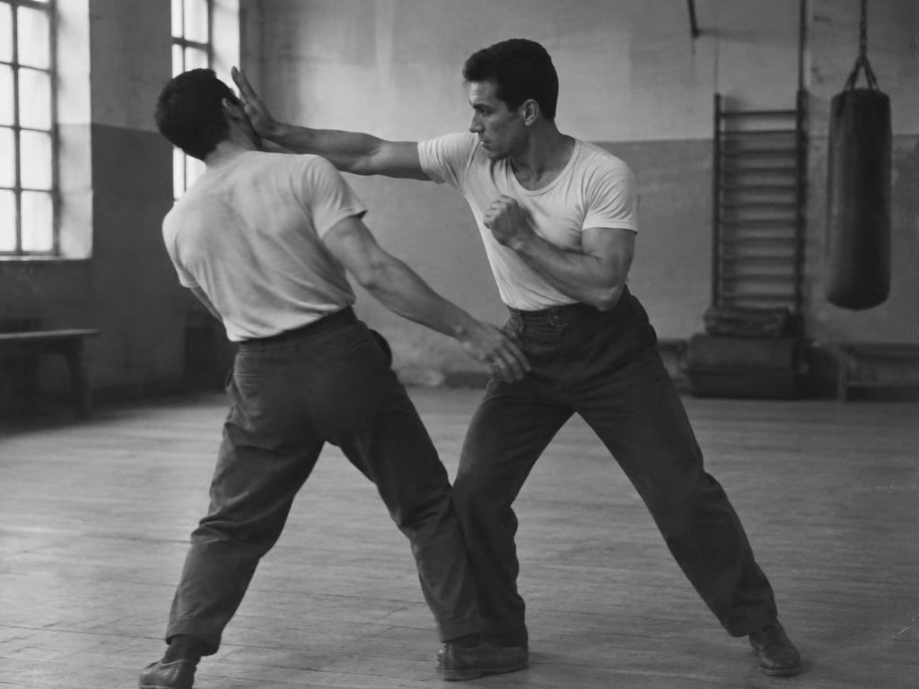 Historical black-and-white photograph: two men practicing a defense against a strike in training